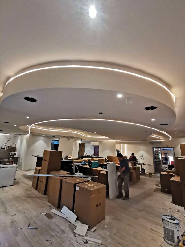 Layered curved ceilings with LED strips over a room full of boxed furniture