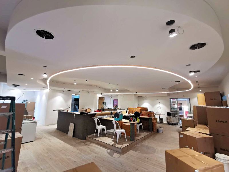 Large oval ceiling with a lit cove over a bar under construction