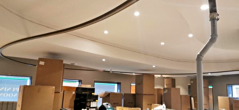 Wave-shaped ceiling bulkhead with pot lights over a room being set up