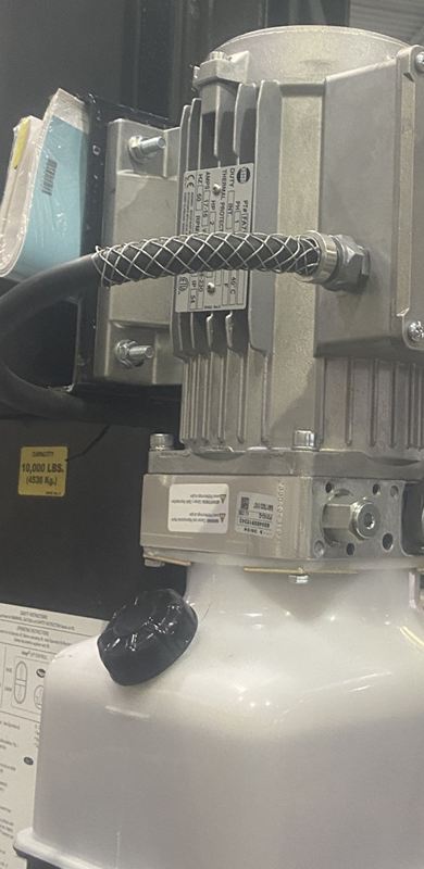 Electric motor and hydraulic power unit mounted on a two-post vehicle hoist in a service bay