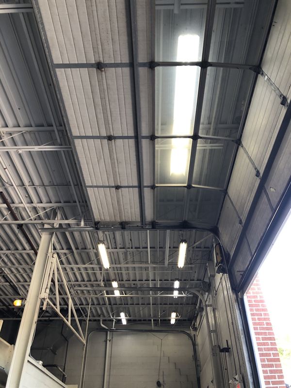 LED strip fixtures in a service bay beside an open overhead door