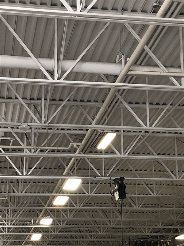LED high-bay fixtures under the steel roof trusses of a service shop