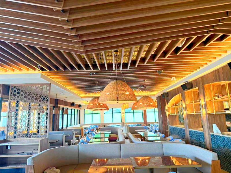 Layered slatted wood ceiling over booth seating, with a laser-cut screen on the left