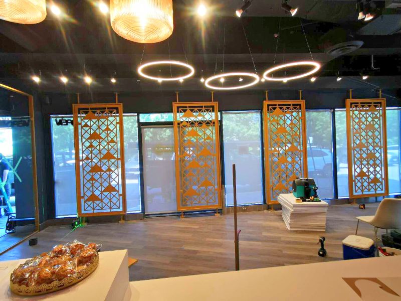 Shop with gold laser-cut screens across the front windows and ring pendant lights